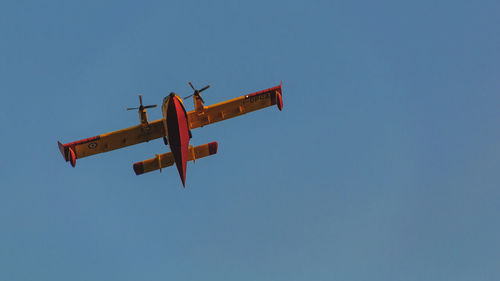 Low angle view of airplane against clear blue sky