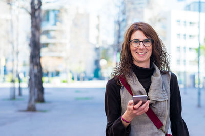 Beautiful woman using mobile while walking on the street