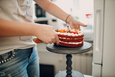 Midsection of woman keeping cake on stand at home