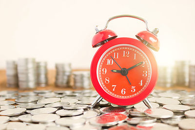 Close-up of alarm clock on coins at table