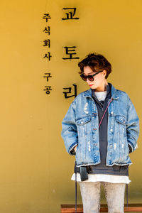 Young man standing against yellow wall