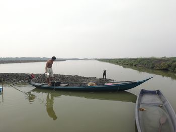 Men standing on boat in lake against sky