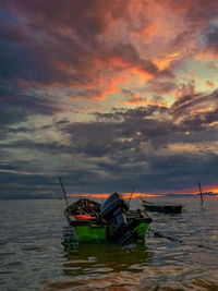 Fishing boat in sea against sky during sunset