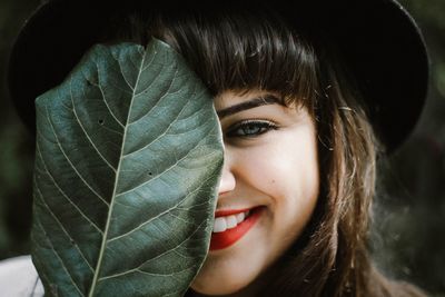 Close-up portrait of smiling woman with leaf