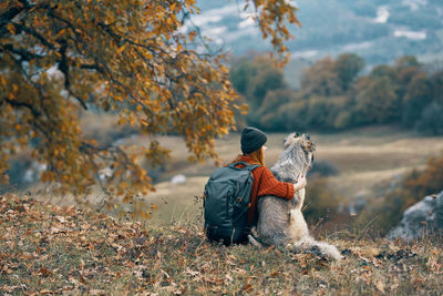 Rear view of man sitting on leaves during autumn