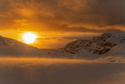 Scenic view of snow covered land against sky during sunset