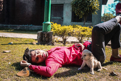 Rear view of child with dog lying down