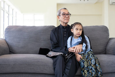 Full length of couple sitting on sofa