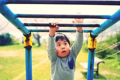 Cute boy playing on monkey bars at playground