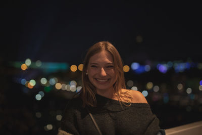 Fashionable young woman in city at night