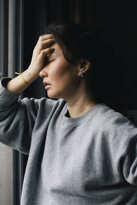 Lonely upset woman with head in hand at home