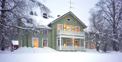 Snow covered houses and trees by house during winter