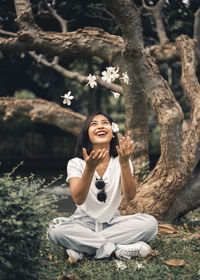 Young woman sitting on tree trunk