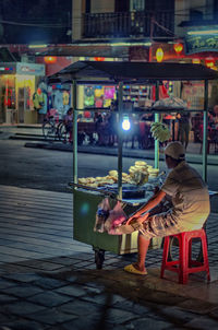 Rear view of vendor with concession stand on sidewalk in city