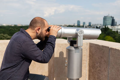 Side view of man looking through binoculars