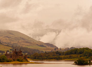 Scenic view of river by mountains against sky