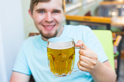 Portrait of smiling young man holding drink