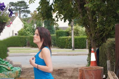 Side view of young woman standing at back yard