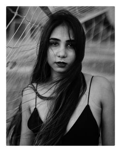 Portrait of beautiful young woman standing against netting