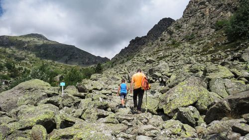 Rear view of men walking on rocks against mountains