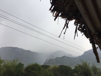 Low angle view of trees and mountains against sky