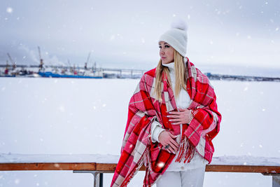Portrait of young woman standing on snow covered field