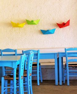 Chairs and tables by wall with paper boat decoration at restaurant