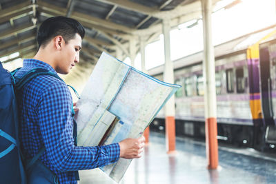 Man standing by train at railroad station