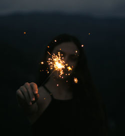 Woman holding illuminated sparkler at night