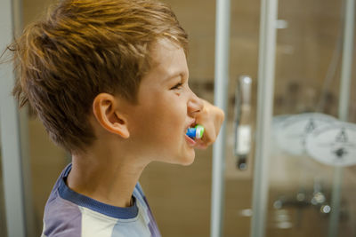 Close-up of boy brushing teeth at bathroom