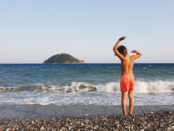 Woman standing at beach against clear sky