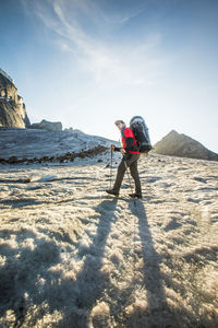 Man with umbrella on snow against sky