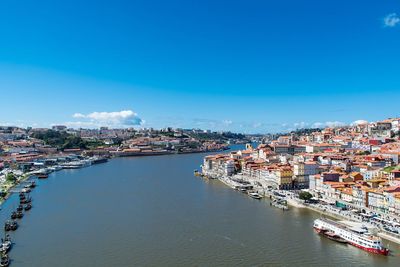 High angle view of townscape by sea against blue sky