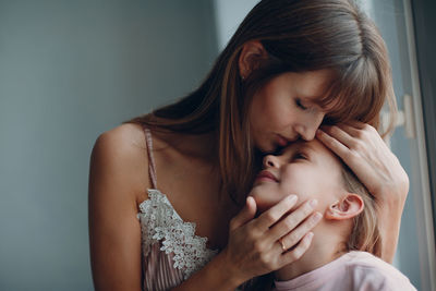 Close-up of mother kissing daughter at home