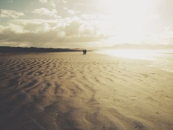 Scenic view of beach against sky at sunset