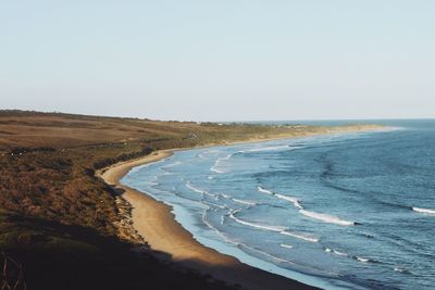 View of calm beach against clear sky