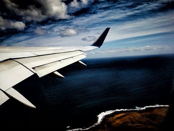 Airplane flying over sea against sky