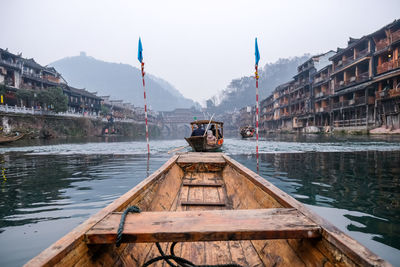 Wooden boat in lake against buildings