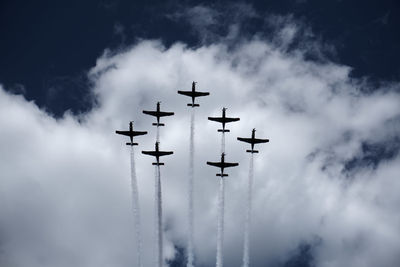 Low angle view of airshow against cloudy sky