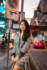 Portrait of smiling young woman standing in city