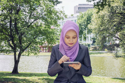 Portrait of mature man holding mobile phone in park