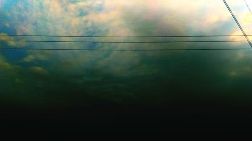 Low angle view of electricity pylon against cloudy sky