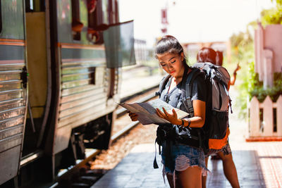 Woman reading map while standing at railroad station platform
