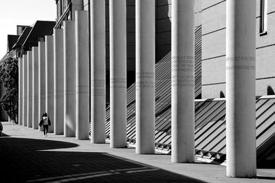 Man walking on street by architectural columns in city