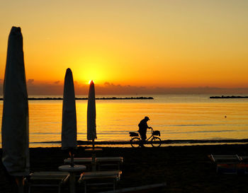 Silhouette people on beach against sky during sunset