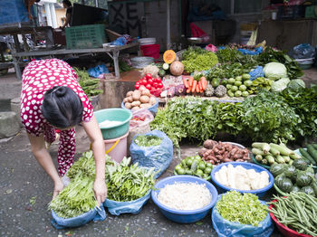 Woman with vegetables for sale at market stall