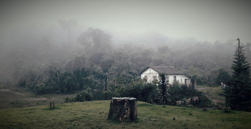 Built structure on field by trees against sky