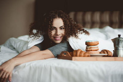 Portrait of smiling woman lying on bead at home