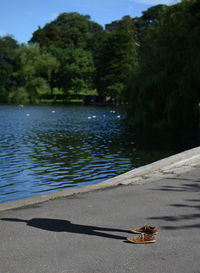 Shadow of man with shoes on footpath by lake