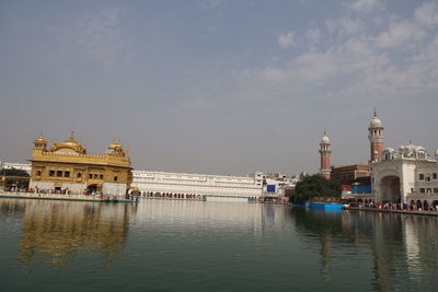 View of buildings by river against sky